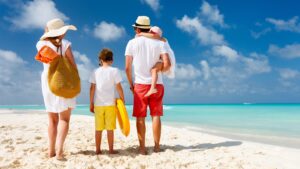 Back view of a happy family at tropical beach on summer vacation